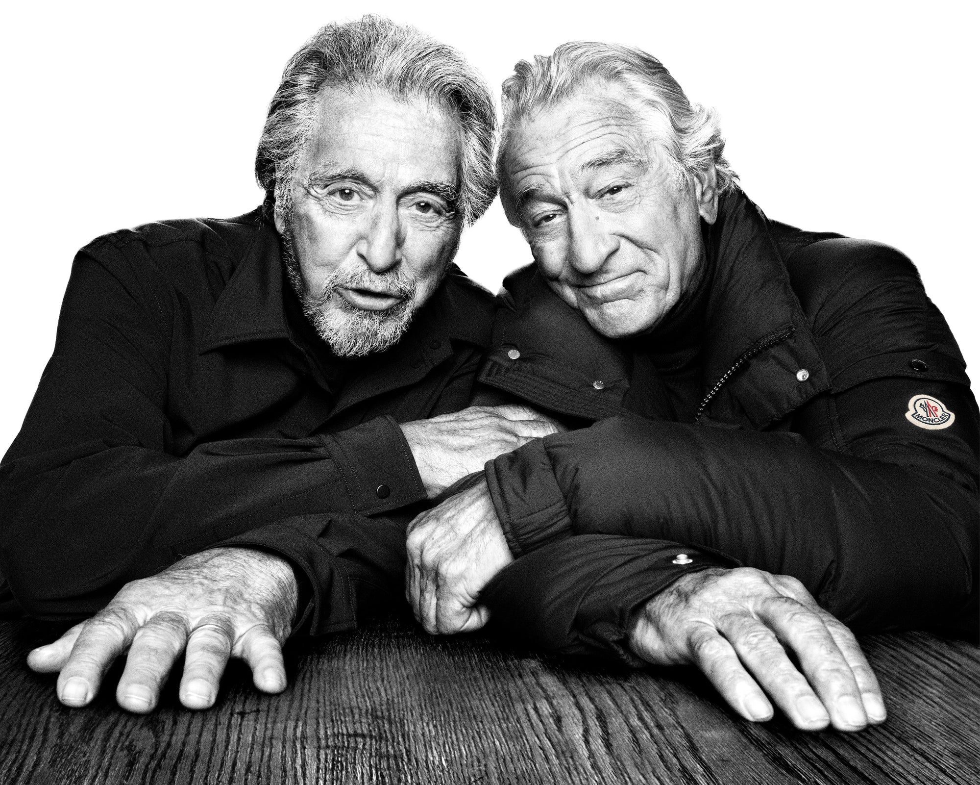 Two men posing closely together with a neutral background