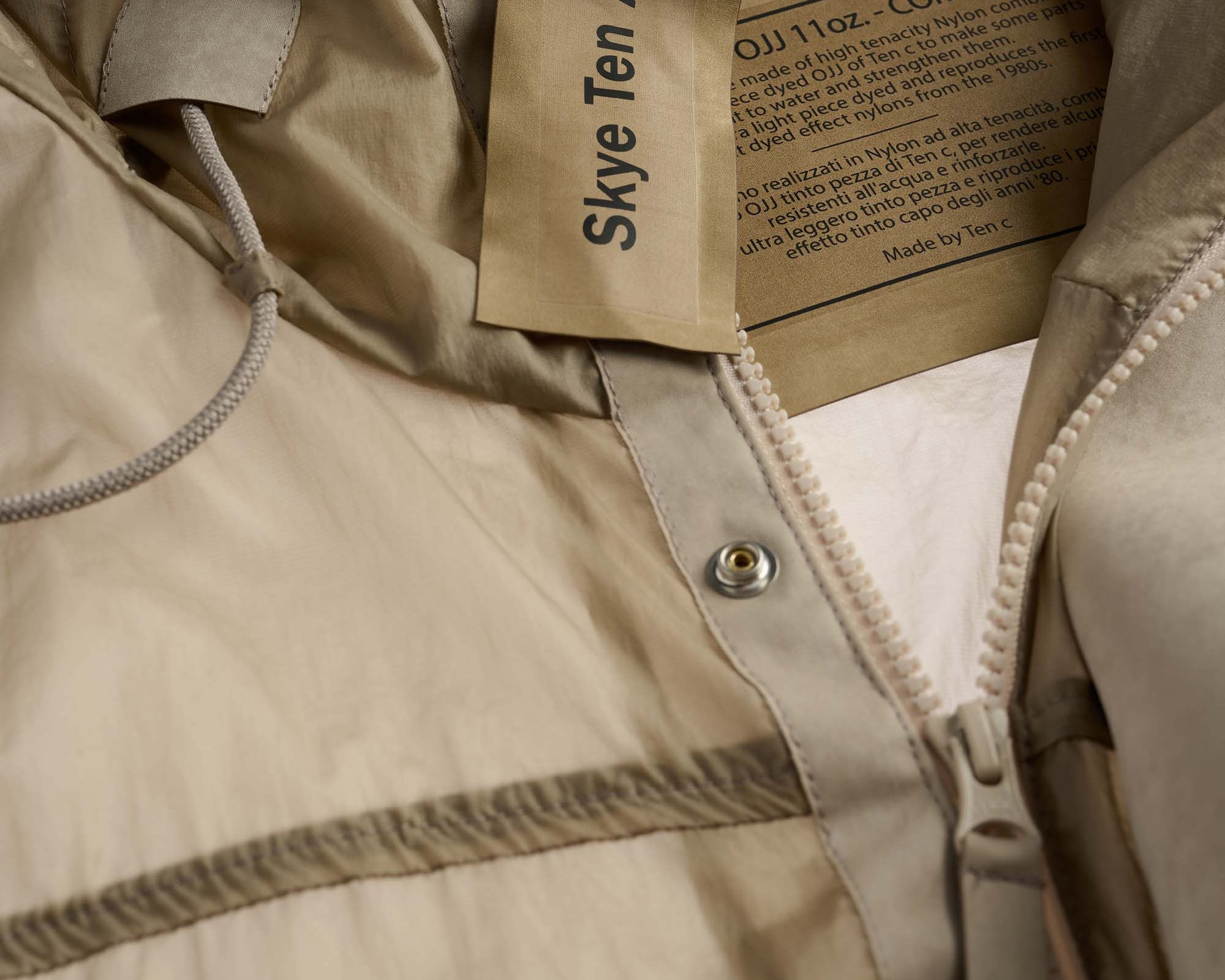 Close-up of a beige jacket with a brand label on a neutral background