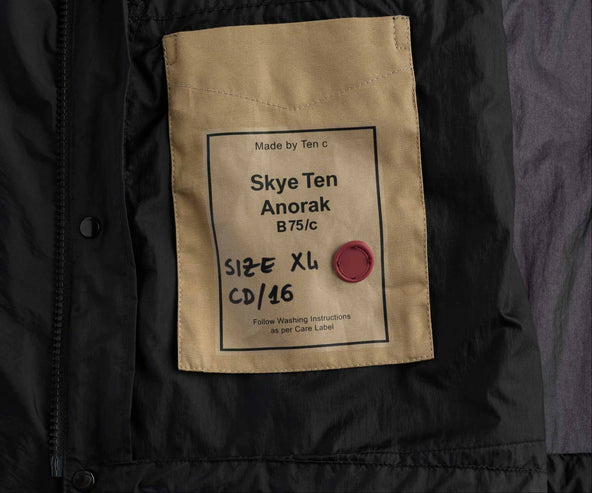 Black jacket with a beige label displaying product details on a white background