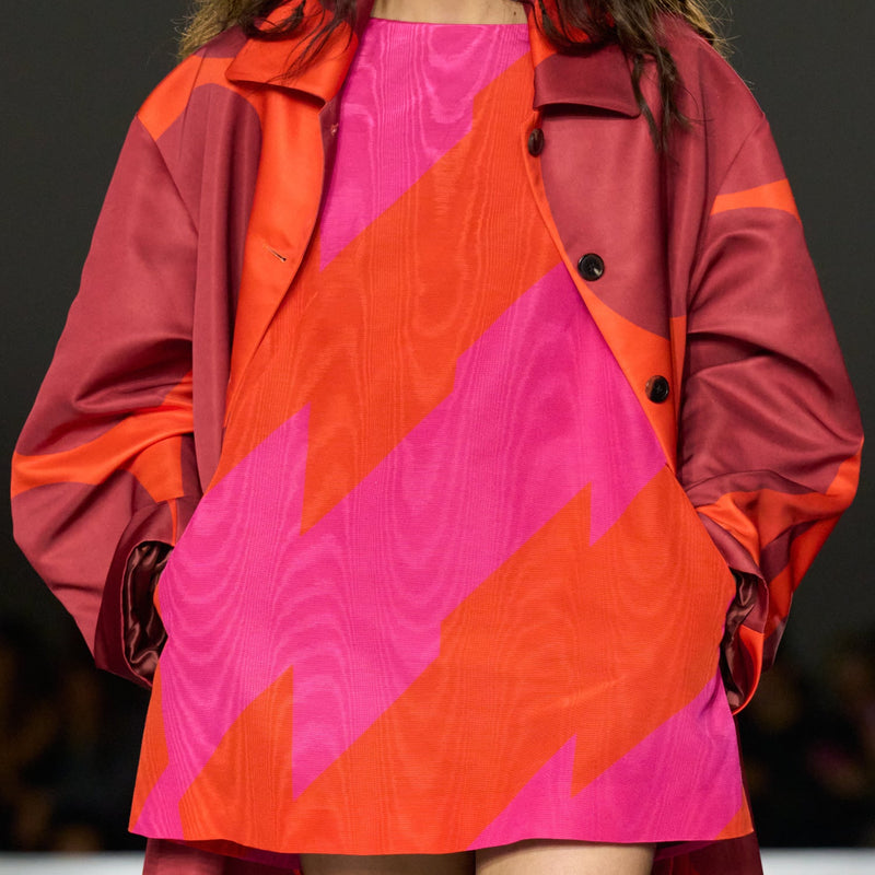 Model wearing Dries Van Noten vibrant red and pink outfit on a runway