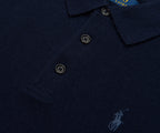 Navy blue polo shirt with brand logo on a dark background