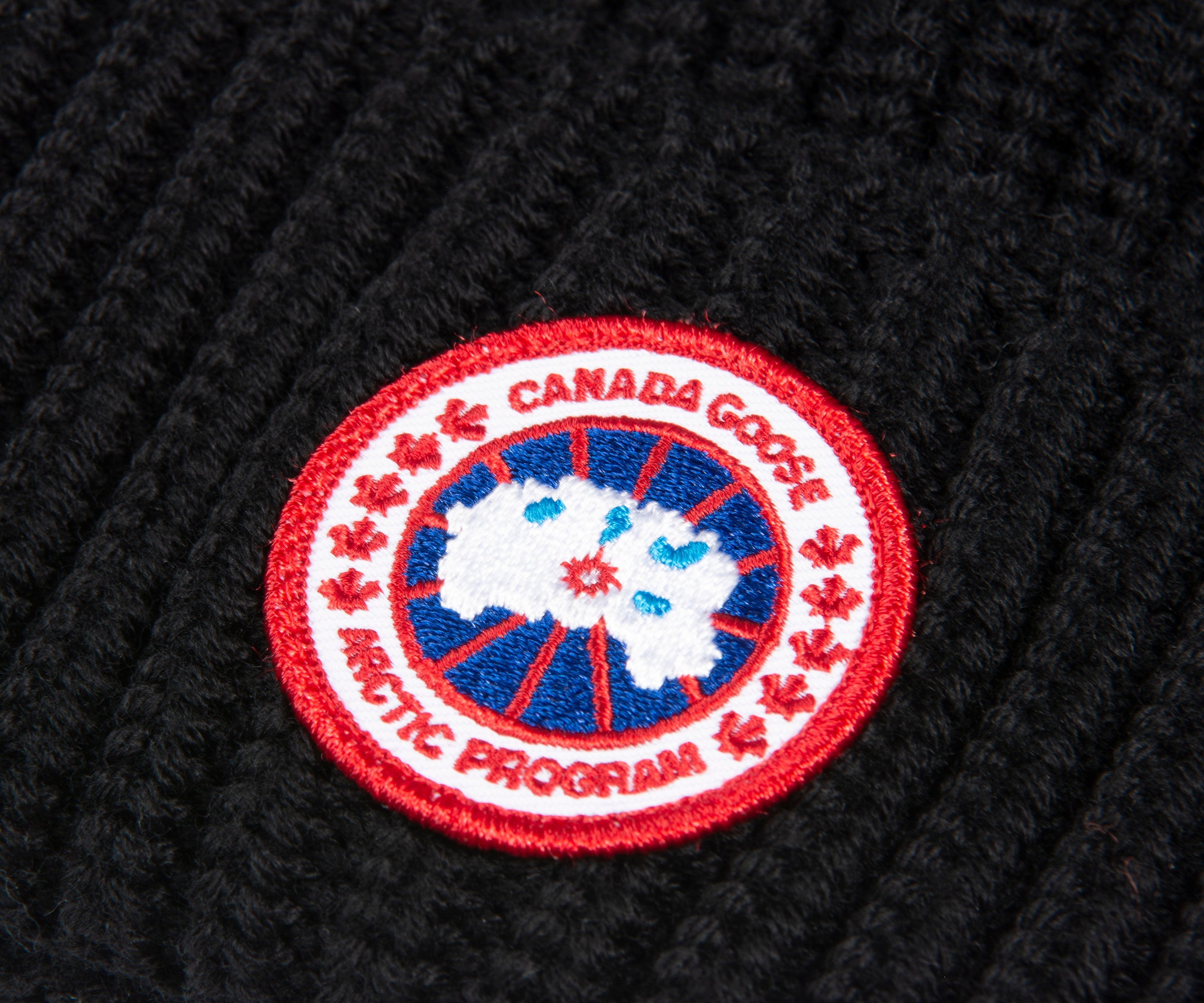 close-up of Canada Goose logo on a black beanie | Pockets