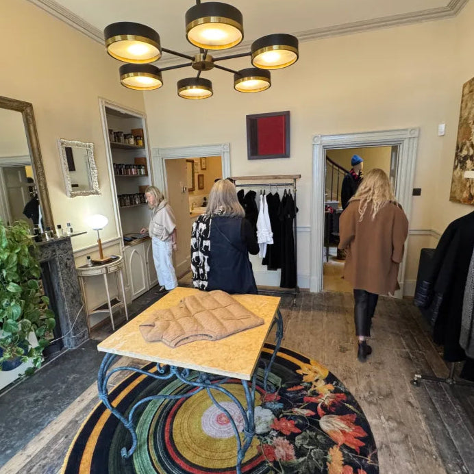 Interior of Pockets clothing store with customers browsing and a chandelier hanging from the ceiling.