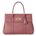 Pink handbag with a gold clasp on a white background