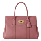Pink handbag with a gold clasp on a white background