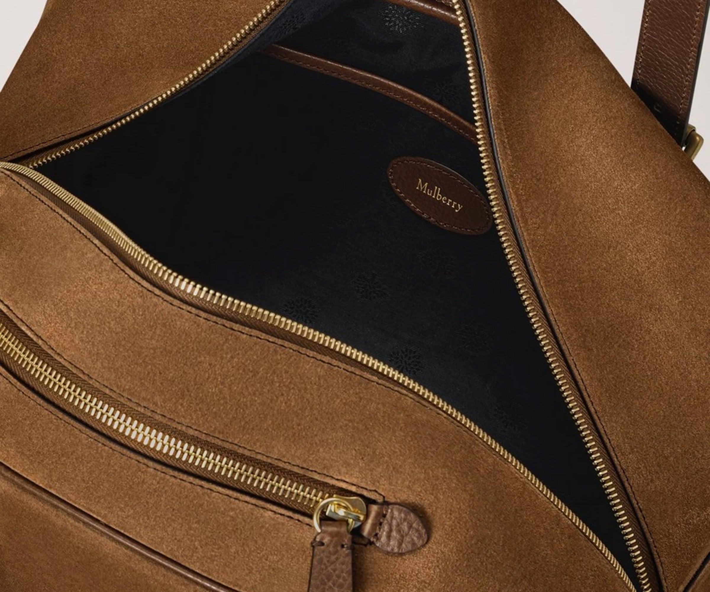 Brown leather bag with gold zipper and 'Mulberry' brand label on a white background