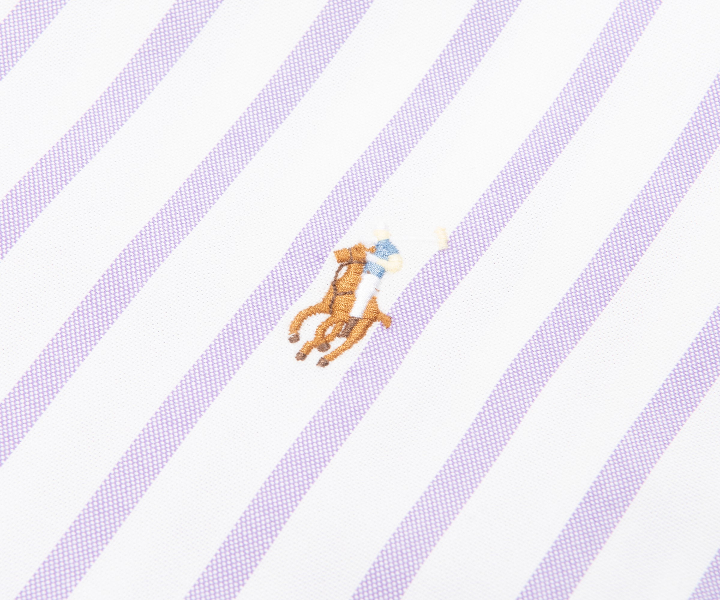 Close-up of a shirt with diagonal stripes and a small logo on a white background