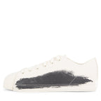 White sneaker with black paint splatter on a white background