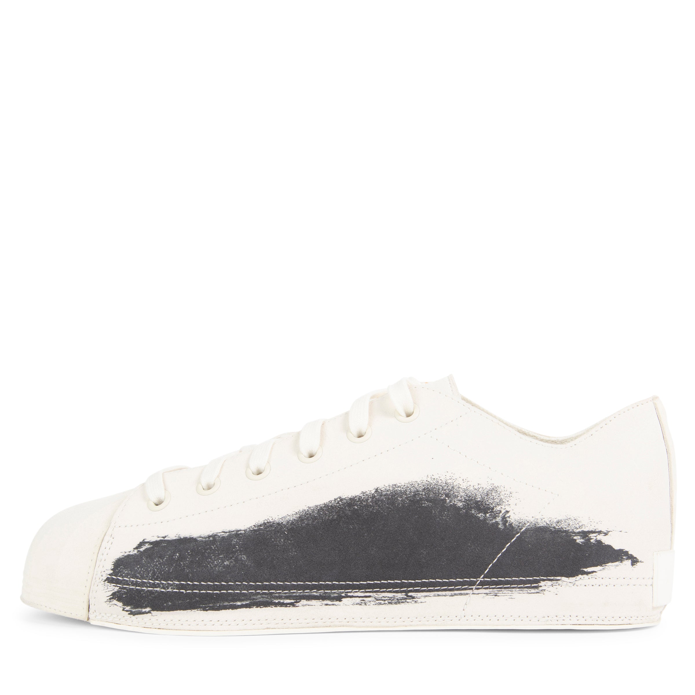 White sneaker with black paint splatter on a white background