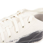 Close-up of a white sneaker with visible wear and tear on a white background