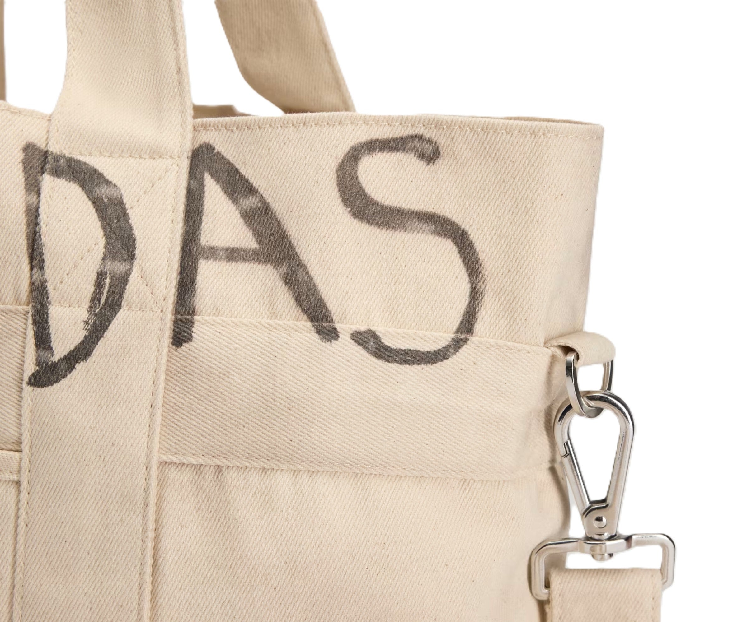 Beige tote bag with 'DAS' printed on it, featuring a metal clasp.