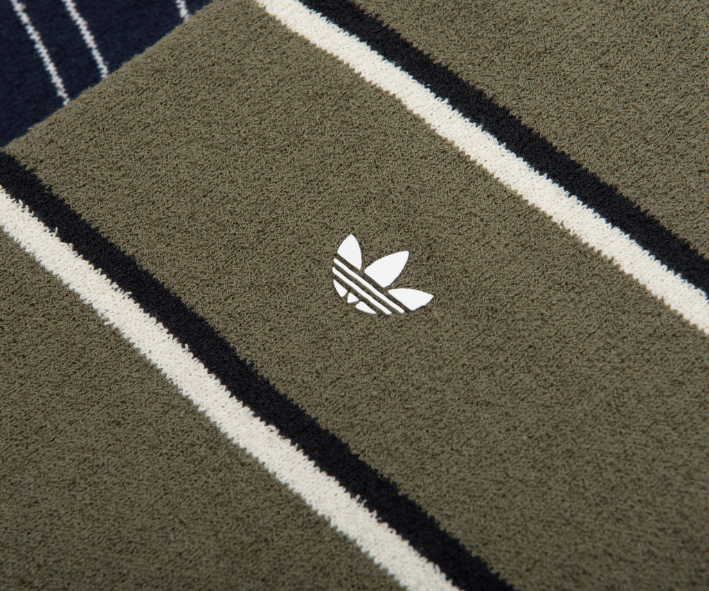 Close-up of a green Adidas towel with a logo on a striped background