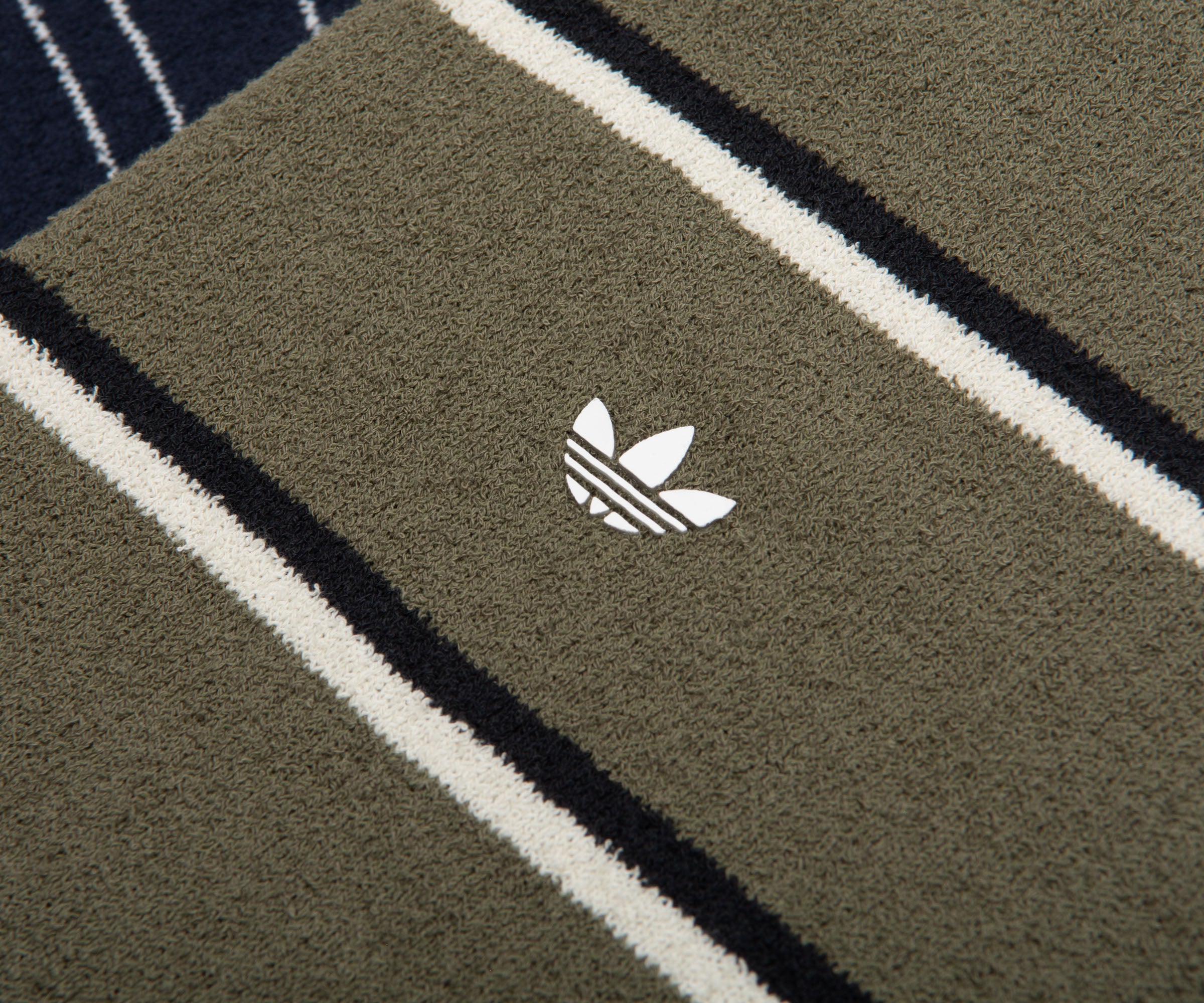 Close-up of a green Adidas towel with a logo on a striped background