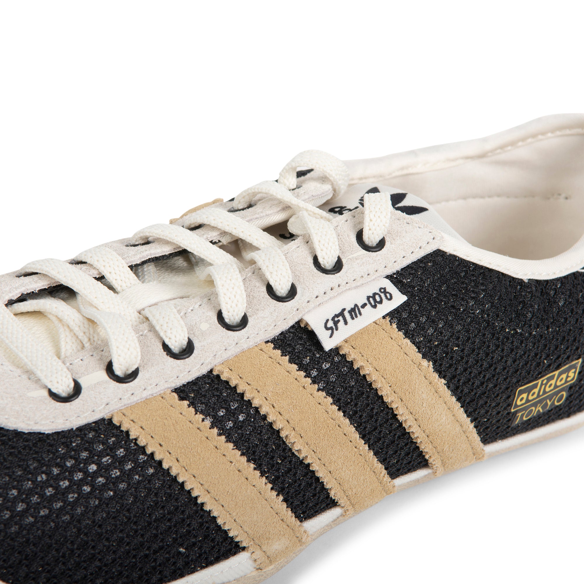 Black and beige Adidas sneaker with white laces on a white background