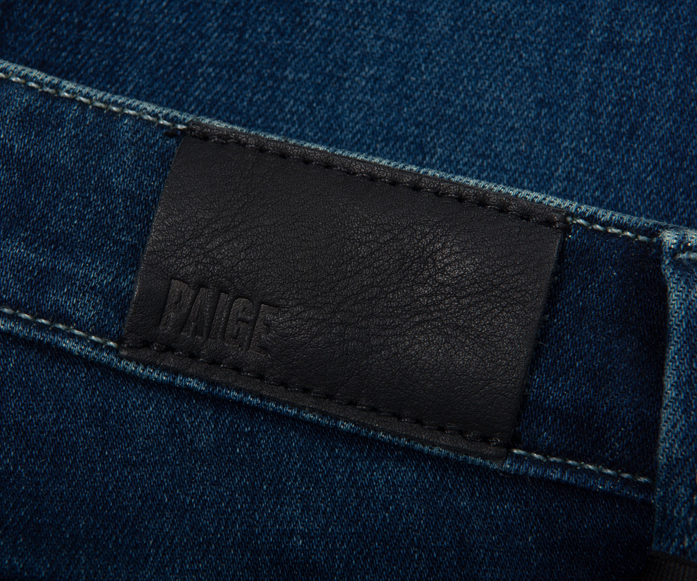 Close-up of a dark blue denim fabric with a black leather label featuring the brand name 'Dante'.