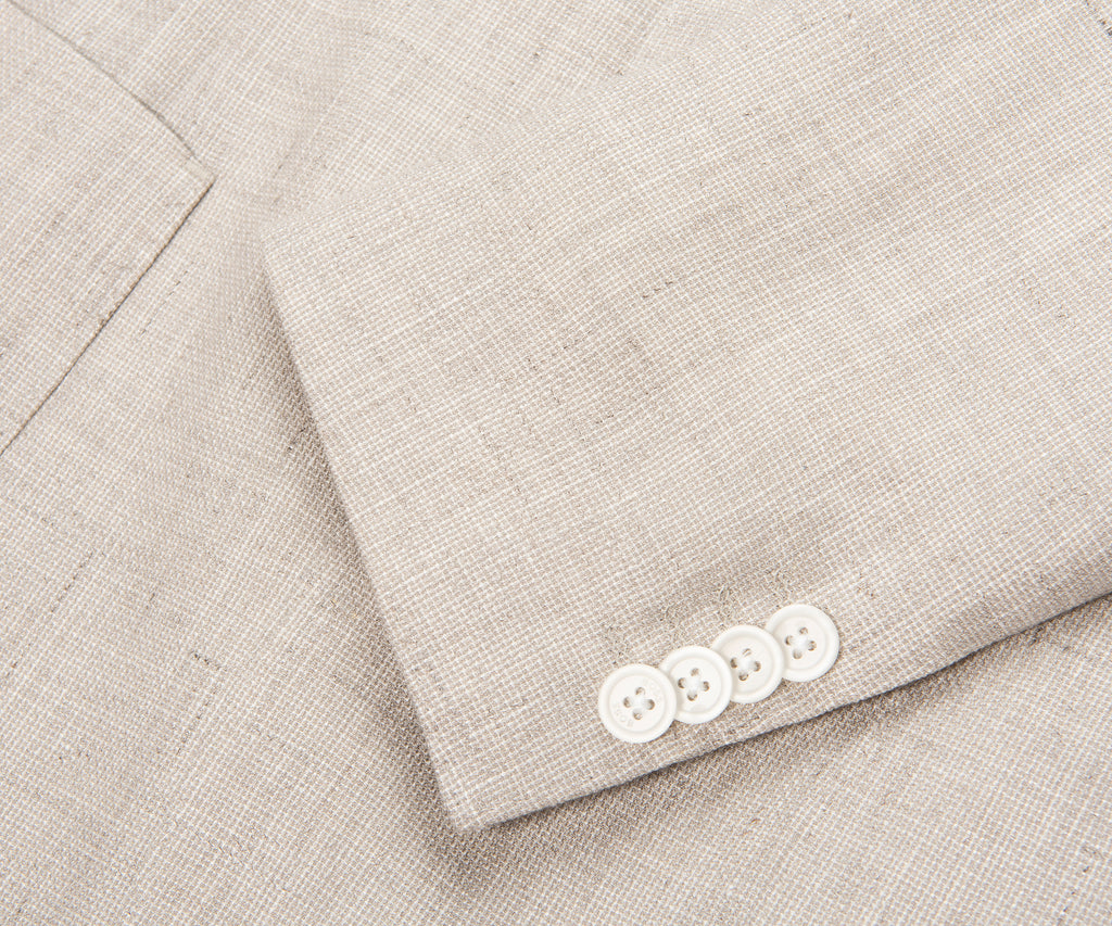 Close-up of a light gray suit with white buttons on a matching fabric background