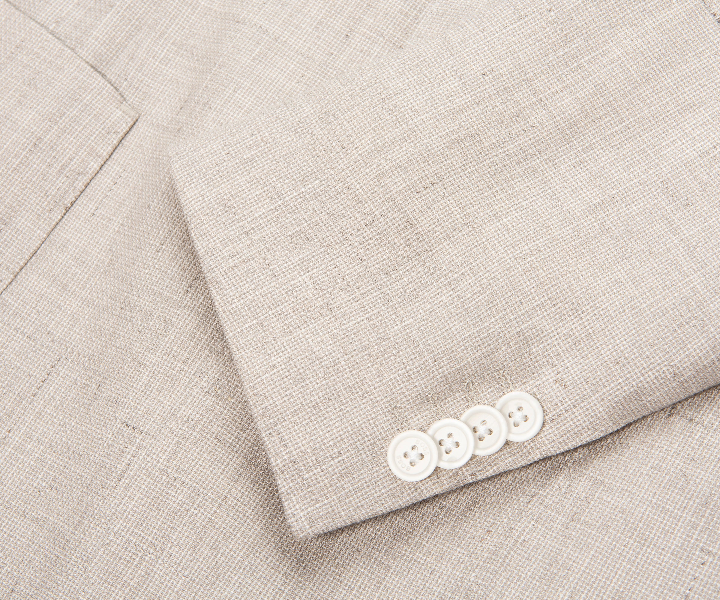Close-up of a light gray suit with white buttons on a matching fabric background