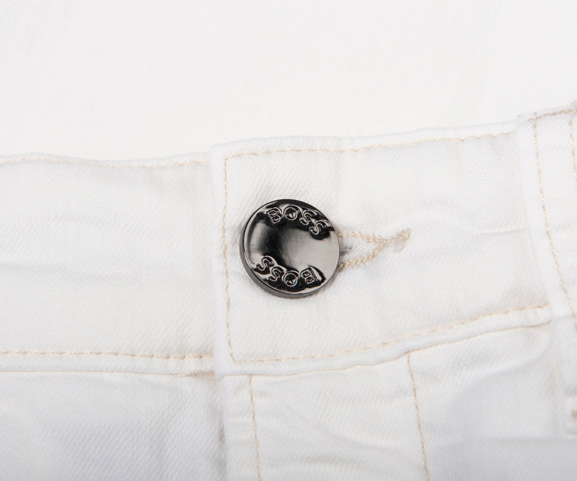 Close-up of a button on white denim fabric