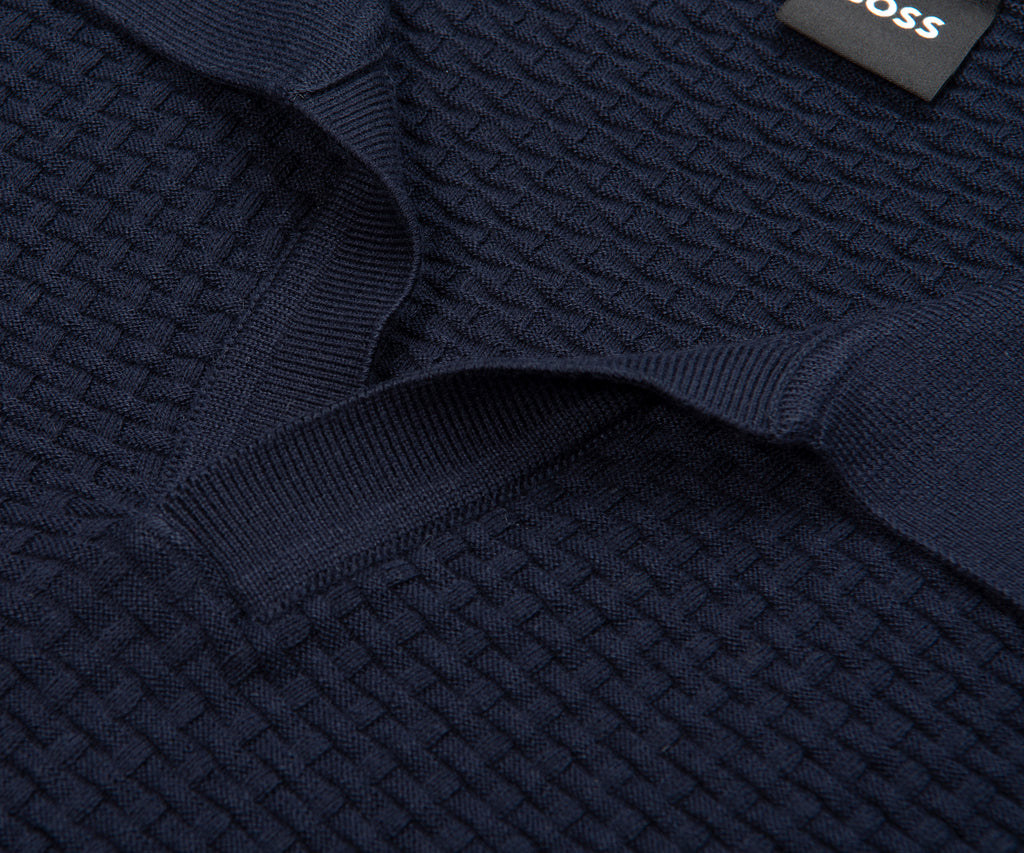 Close-up of a navy blue textured sweater with a brand label.