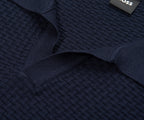 Close-up of a navy blue textured sweater with a brand label.