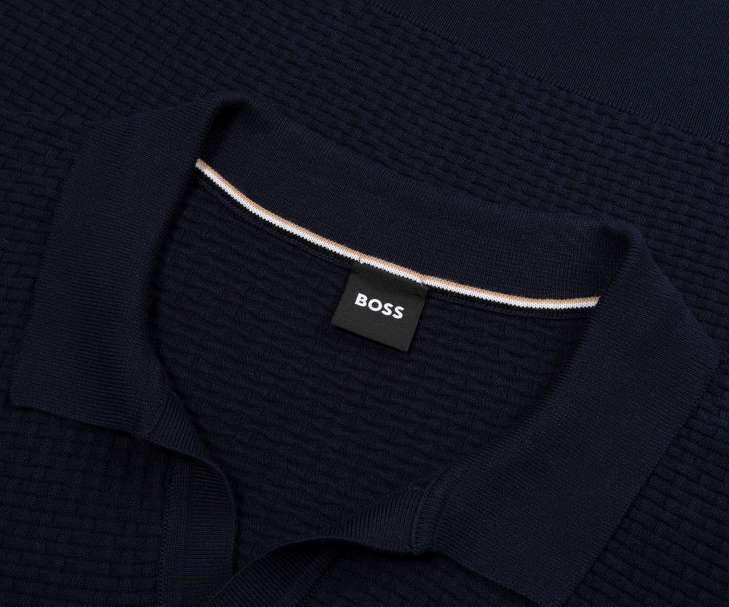 Dark blue textured sweater with a visible brand label on a dark background