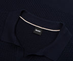 Dark blue textured sweater with a visible brand label on a dark background
