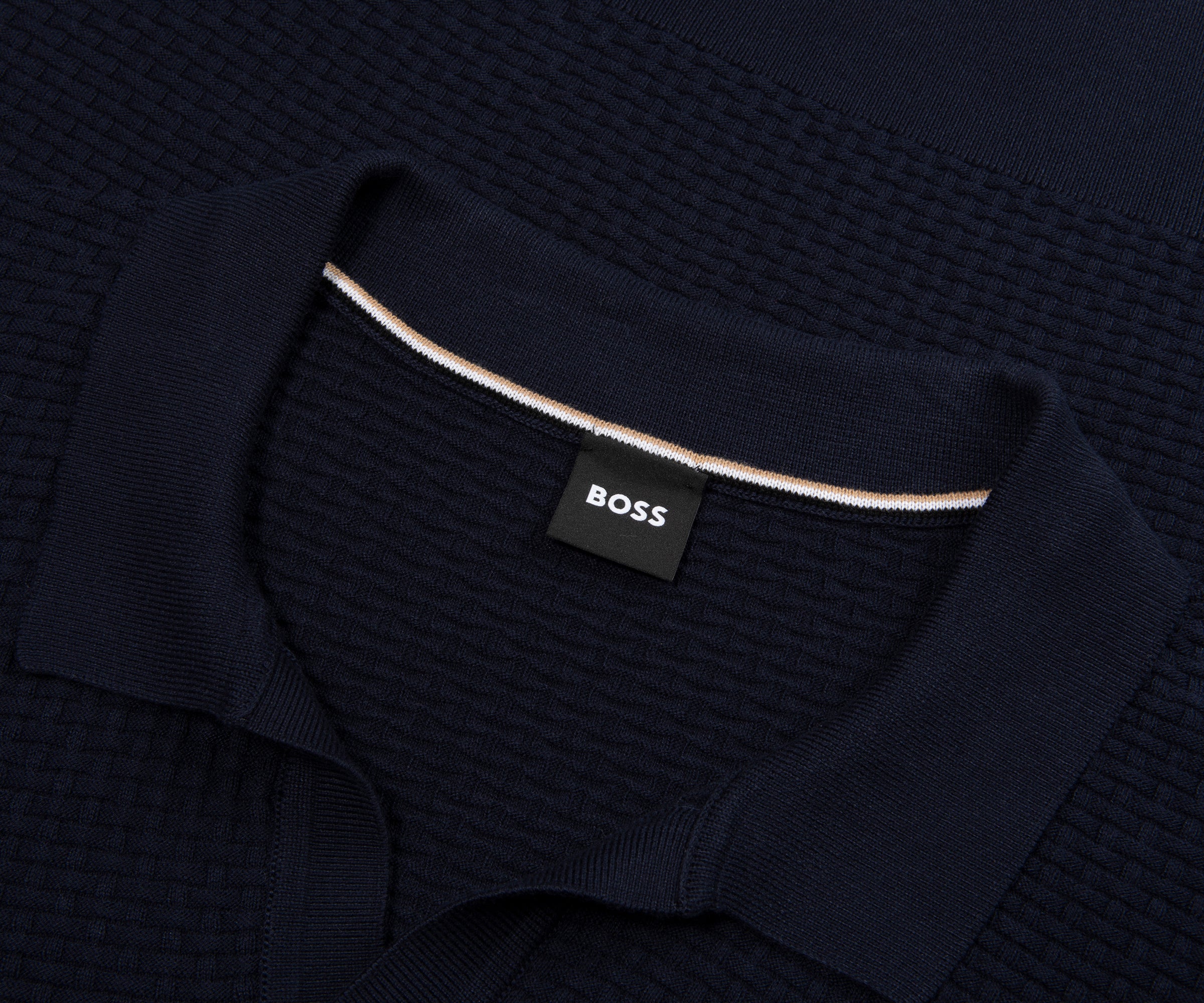 Dark blue textured sweater with a visible brand label on a dark background