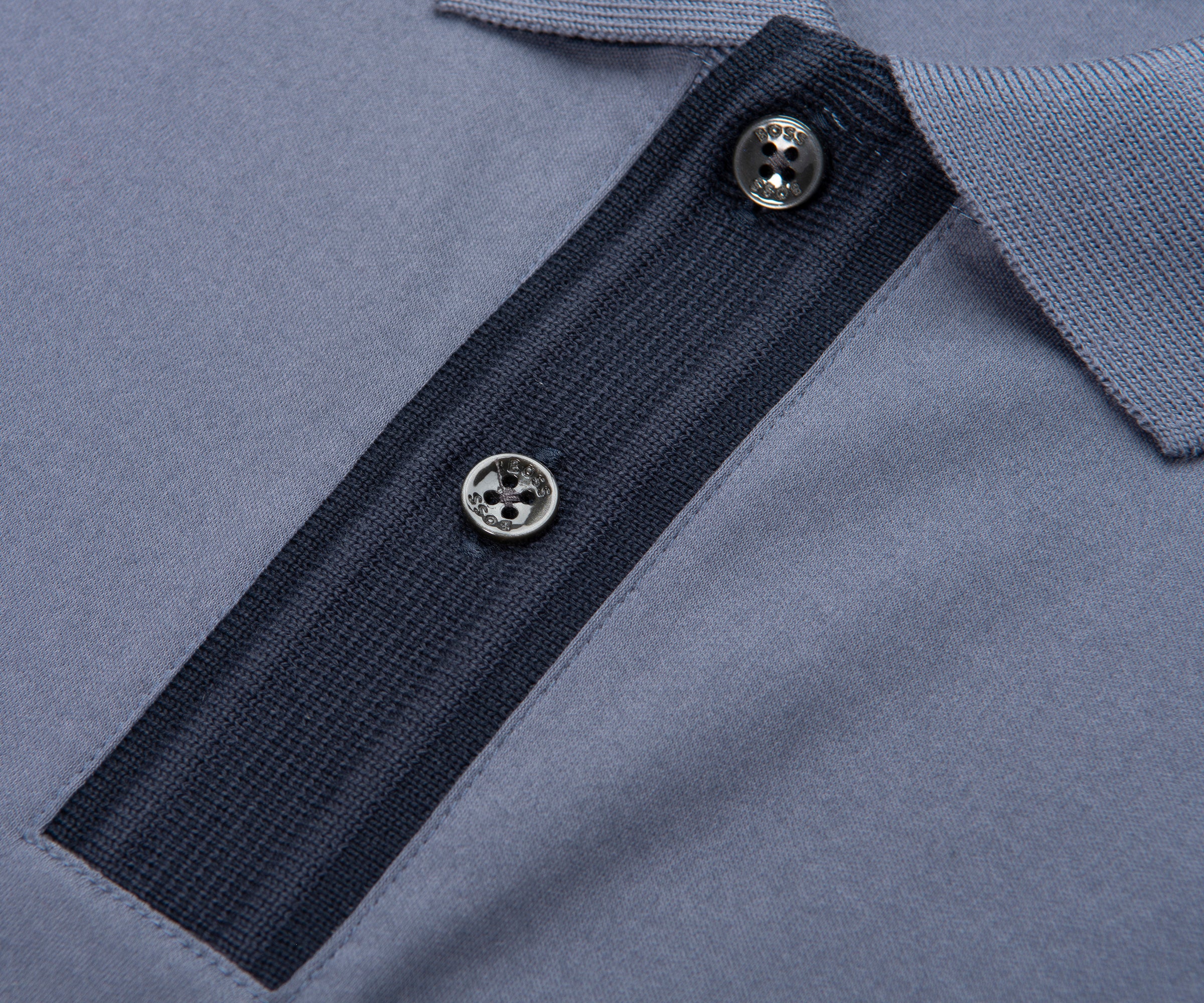 Close-up of a blue polo shirt with black trim and buttons.