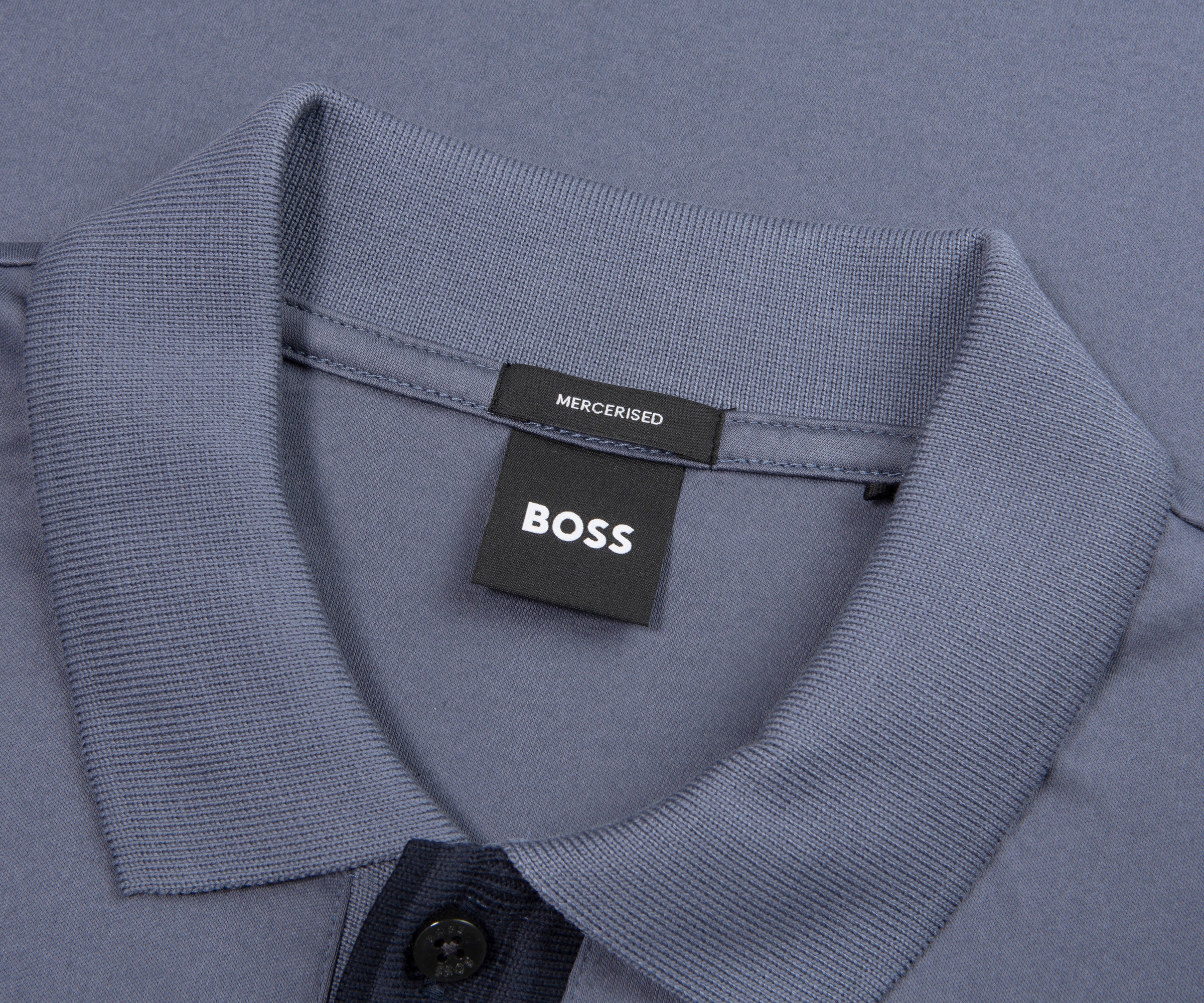 Close-up of a blue shirt collar with a BOSS label on a gray background
