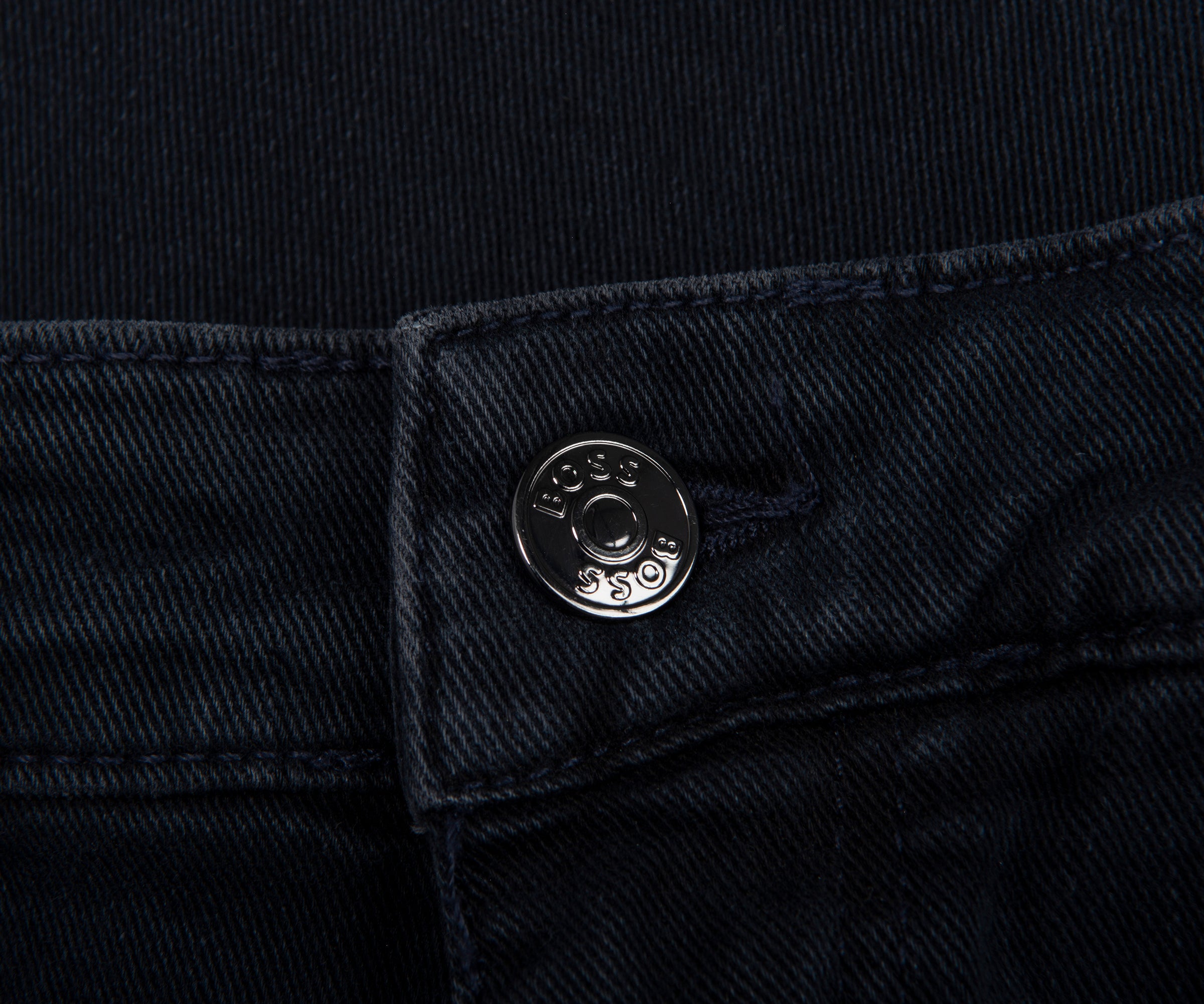 Close-up of a button on black denim fabric