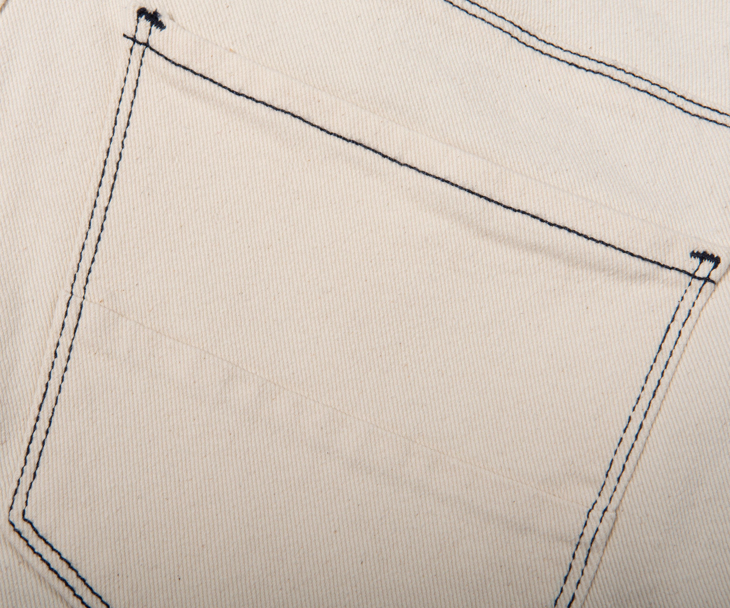 Close-up of a pocket on beige fabric with black stitching