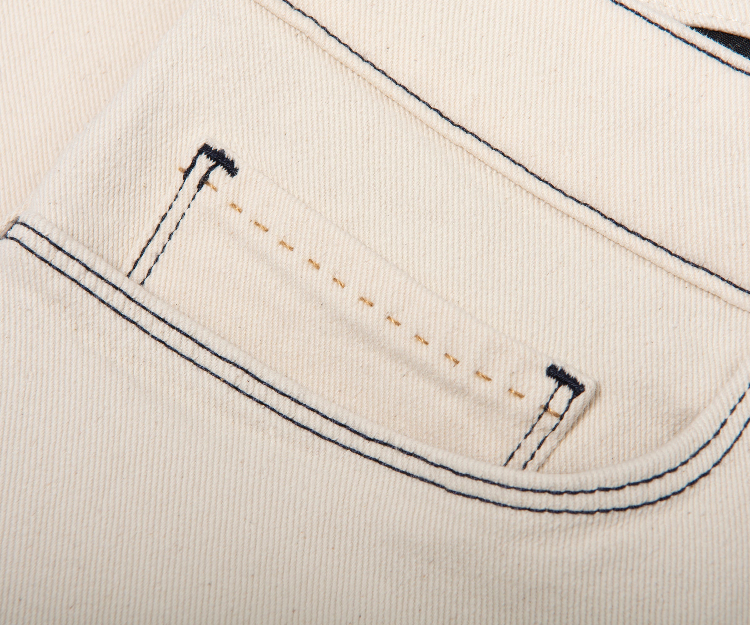 Close-up of a pocket on beige fabric with black stitching
