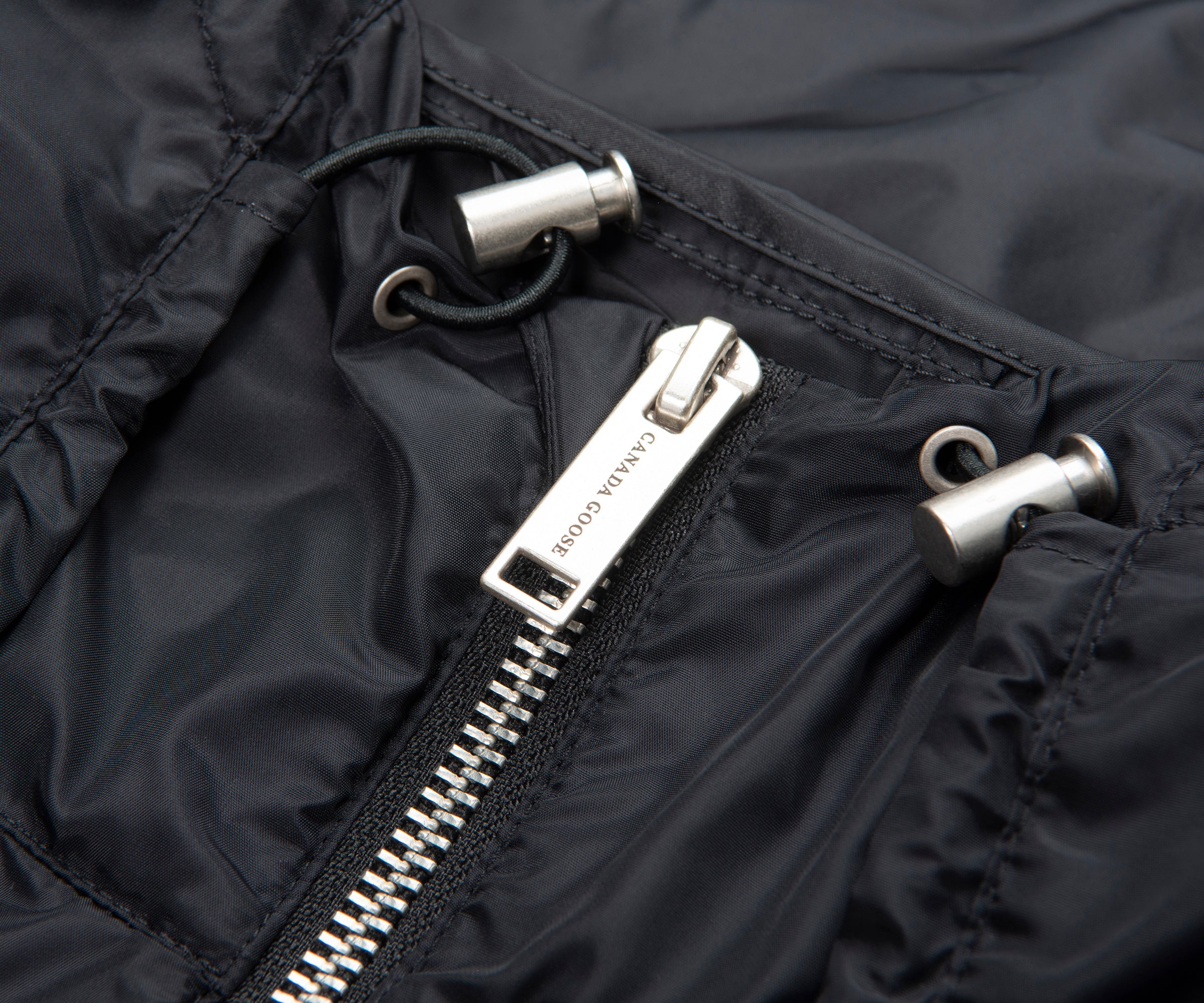 Close-up of a black jacket zipper with a brand logo.