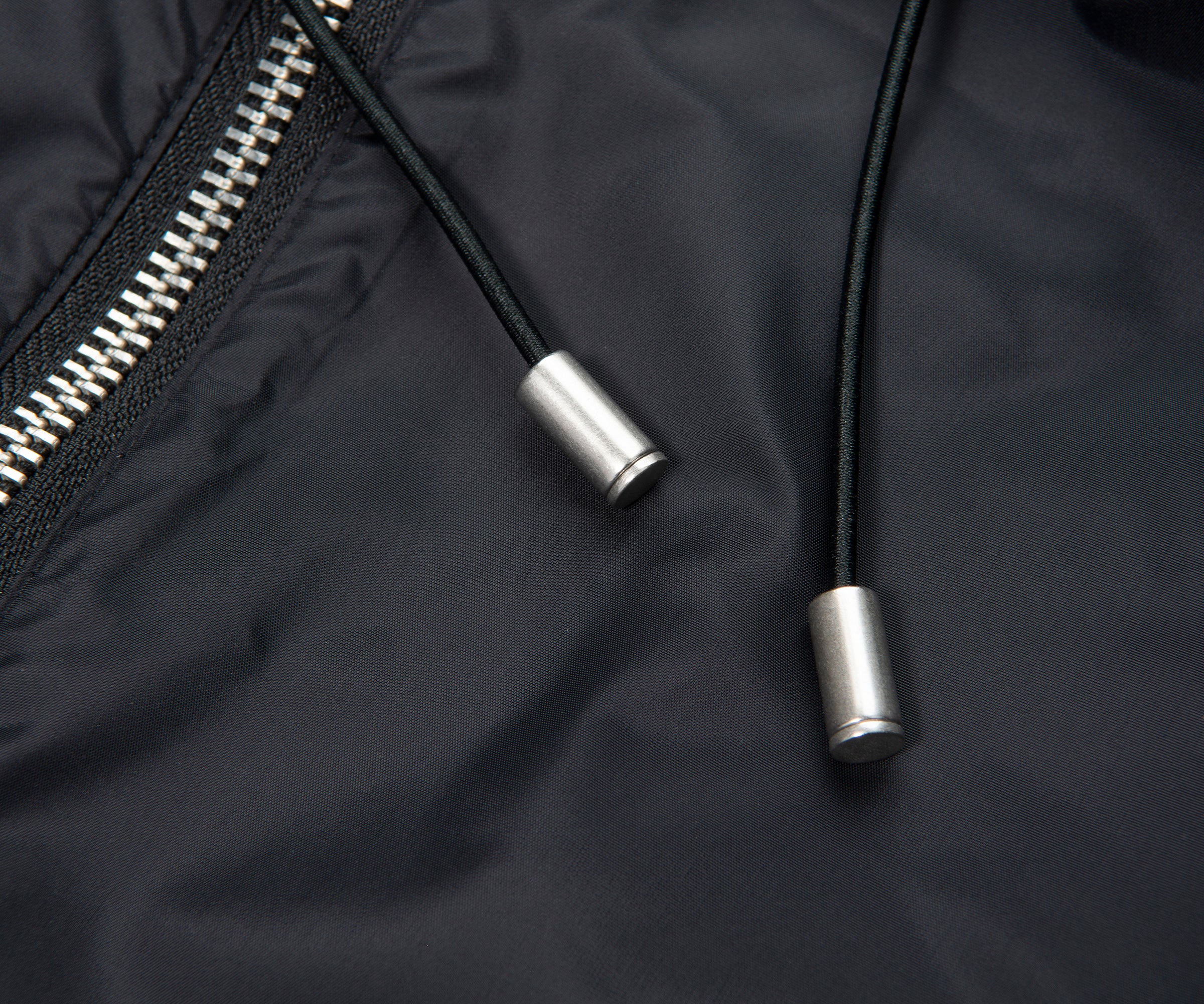 Close-up of a black jacket with a zipper and drawstrings on a dark background
