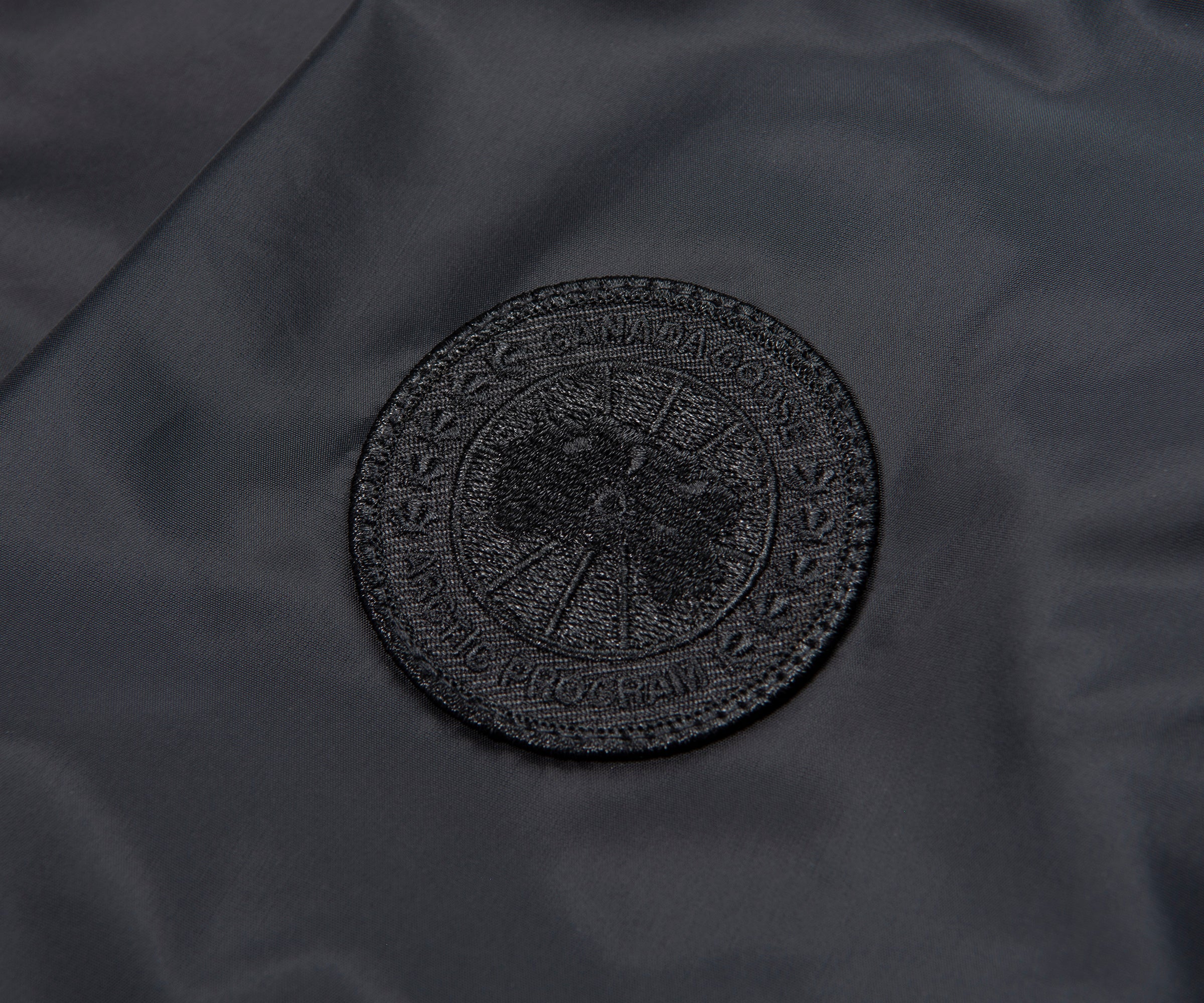 Black circular logo on a dark fabric background