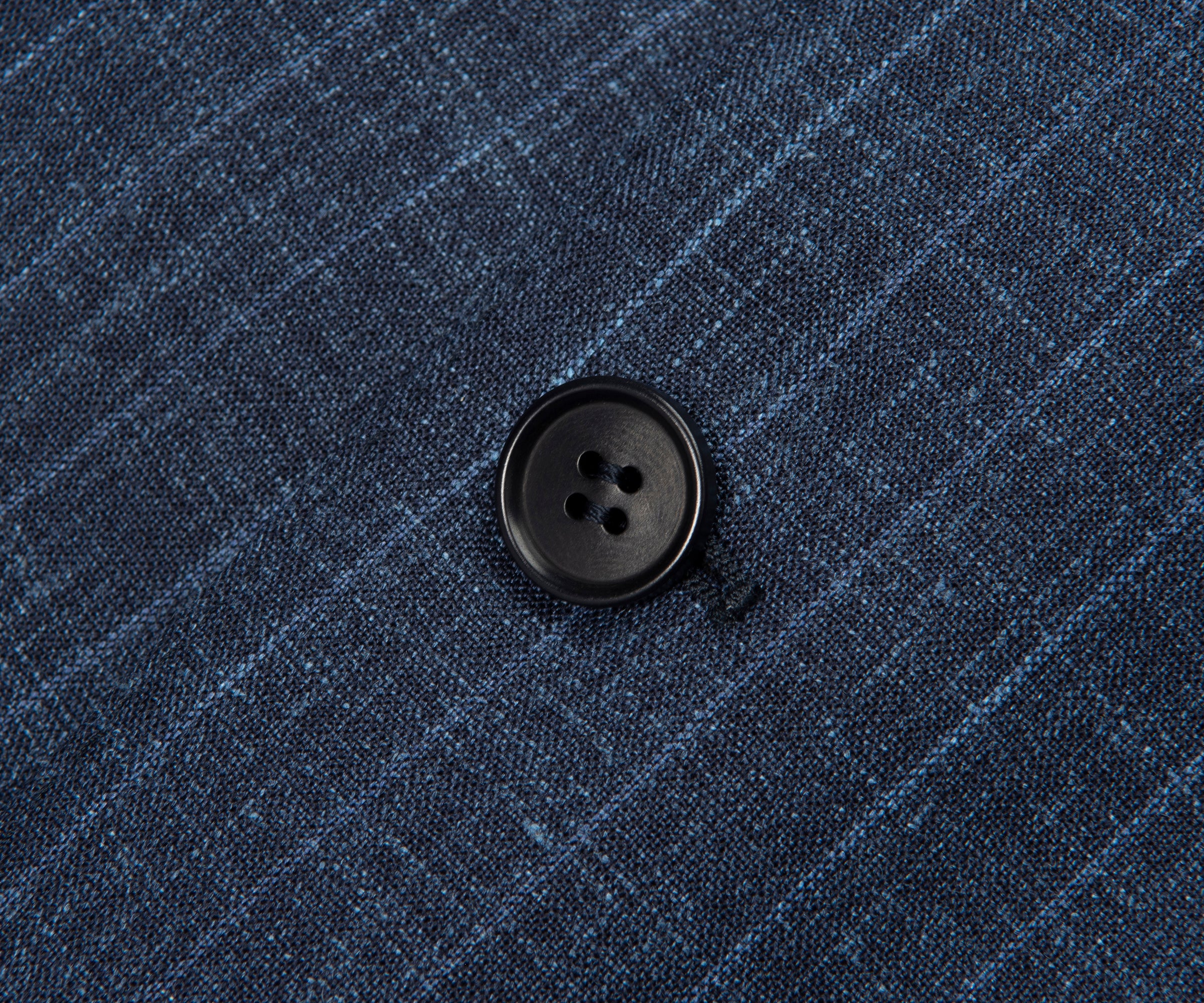 Close-up of a button on a blue checkered fabric