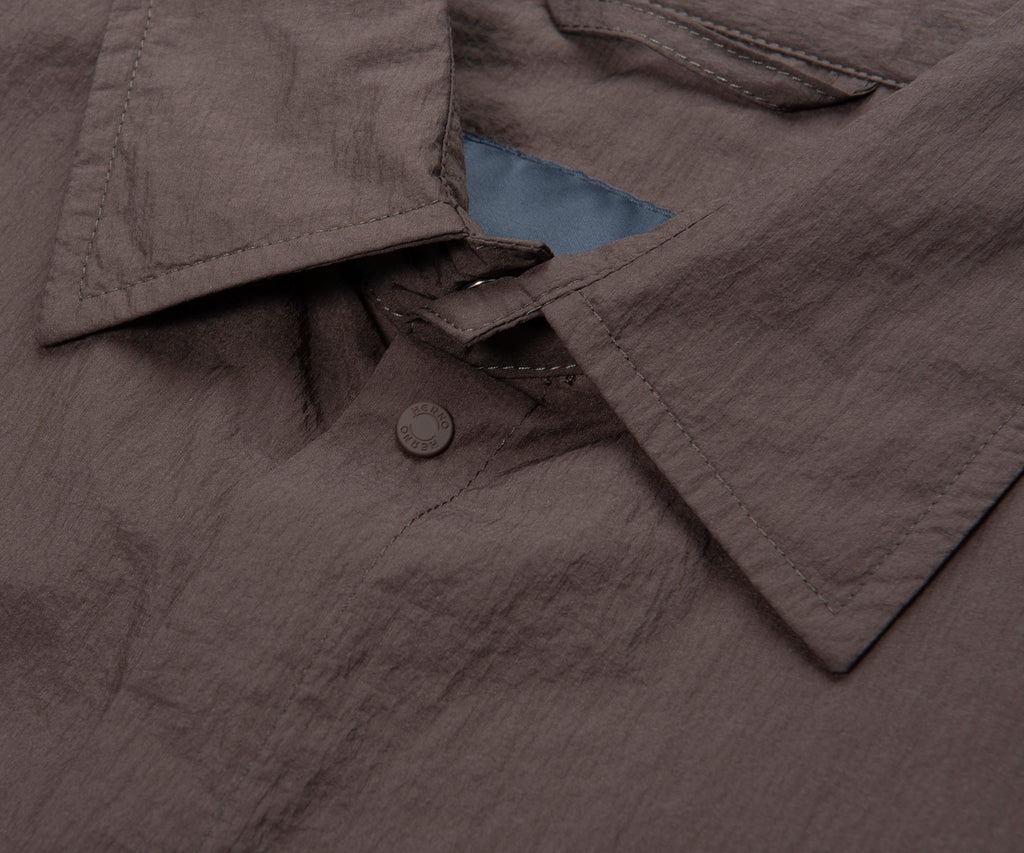 Close-up of a gray jacket with a button and blue lining.
