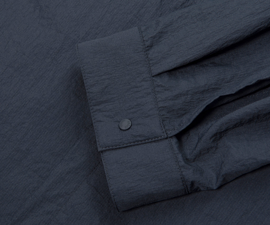 Close-up of a dark gray shirt with rolled-up sleeve on a matching fabric background