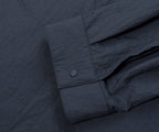 Close-up of a dark gray shirt with rolled-up sleeve on a matching fabric background