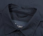 Close-up of a dark blue shirt with a collar and buttons, featuring the brand name 'Bella+Canvas'.