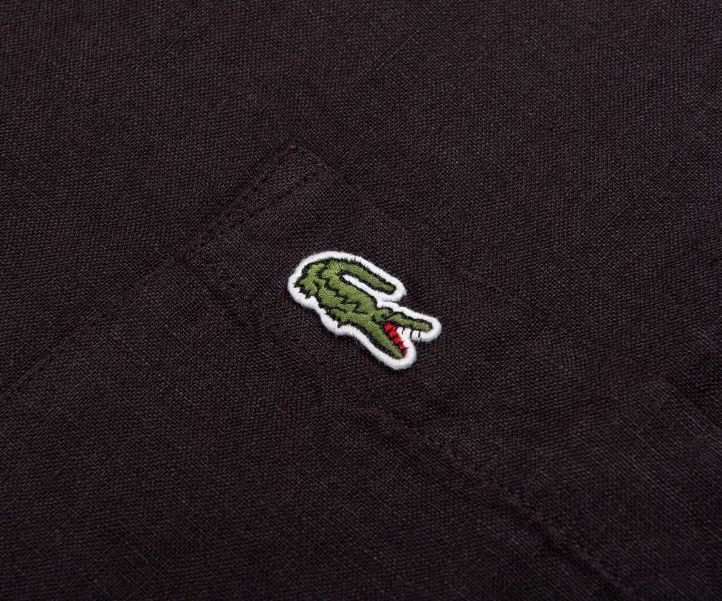Close-up of a black fabric with a green and red embroidered crocodile logo.