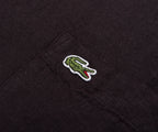 Close-up of a black fabric with a green and red embroidered crocodile logo.