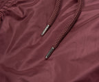 Brown braided shoelace with metal eyelets on a maroon fabric background