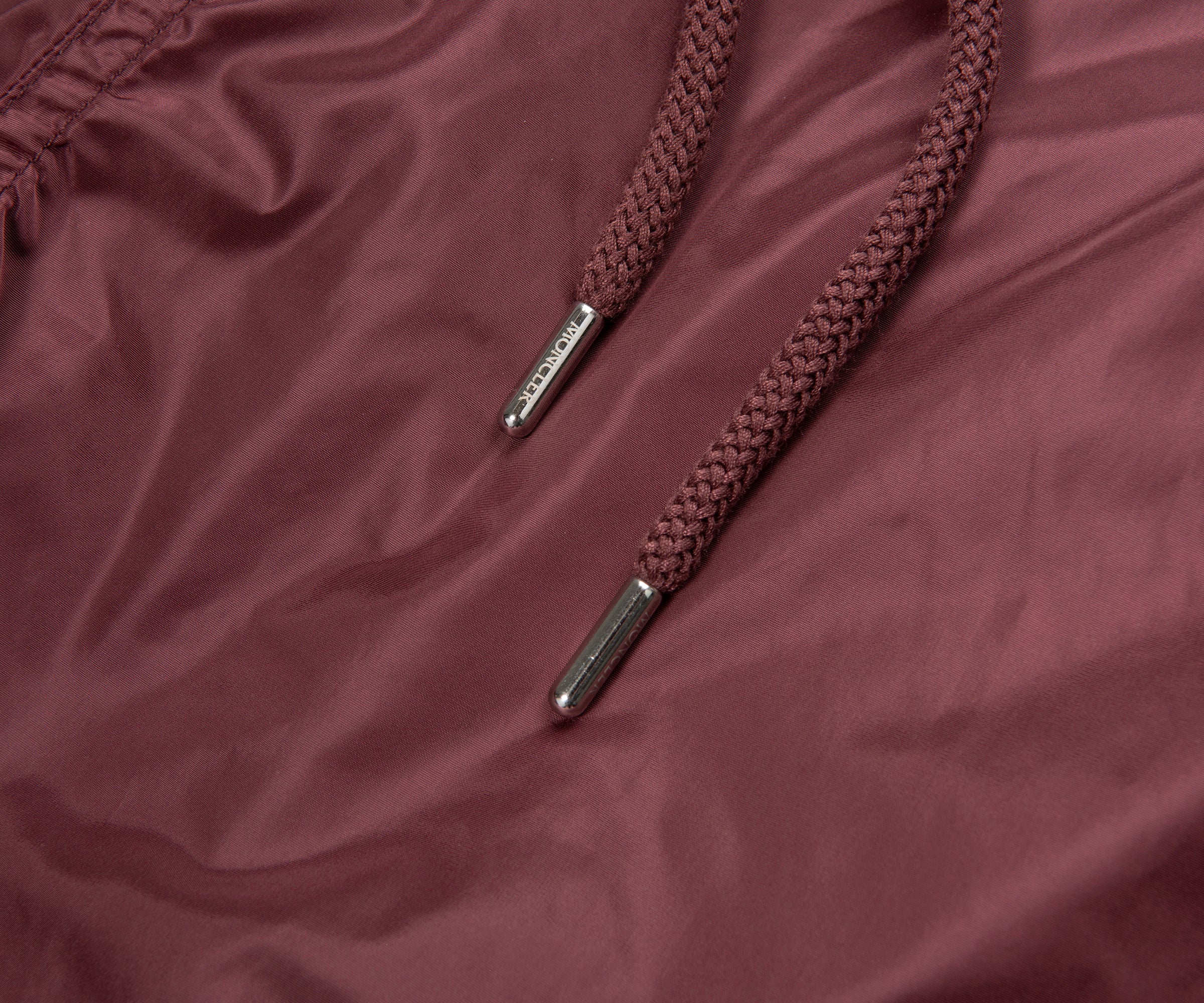 Brown braided shoelace with metal eyelets on a maroon fabric background