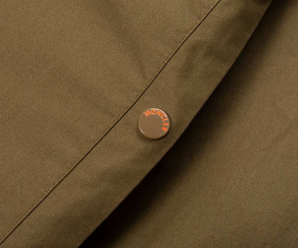 Close-up of a brown jacket with a brand logo on a matching background