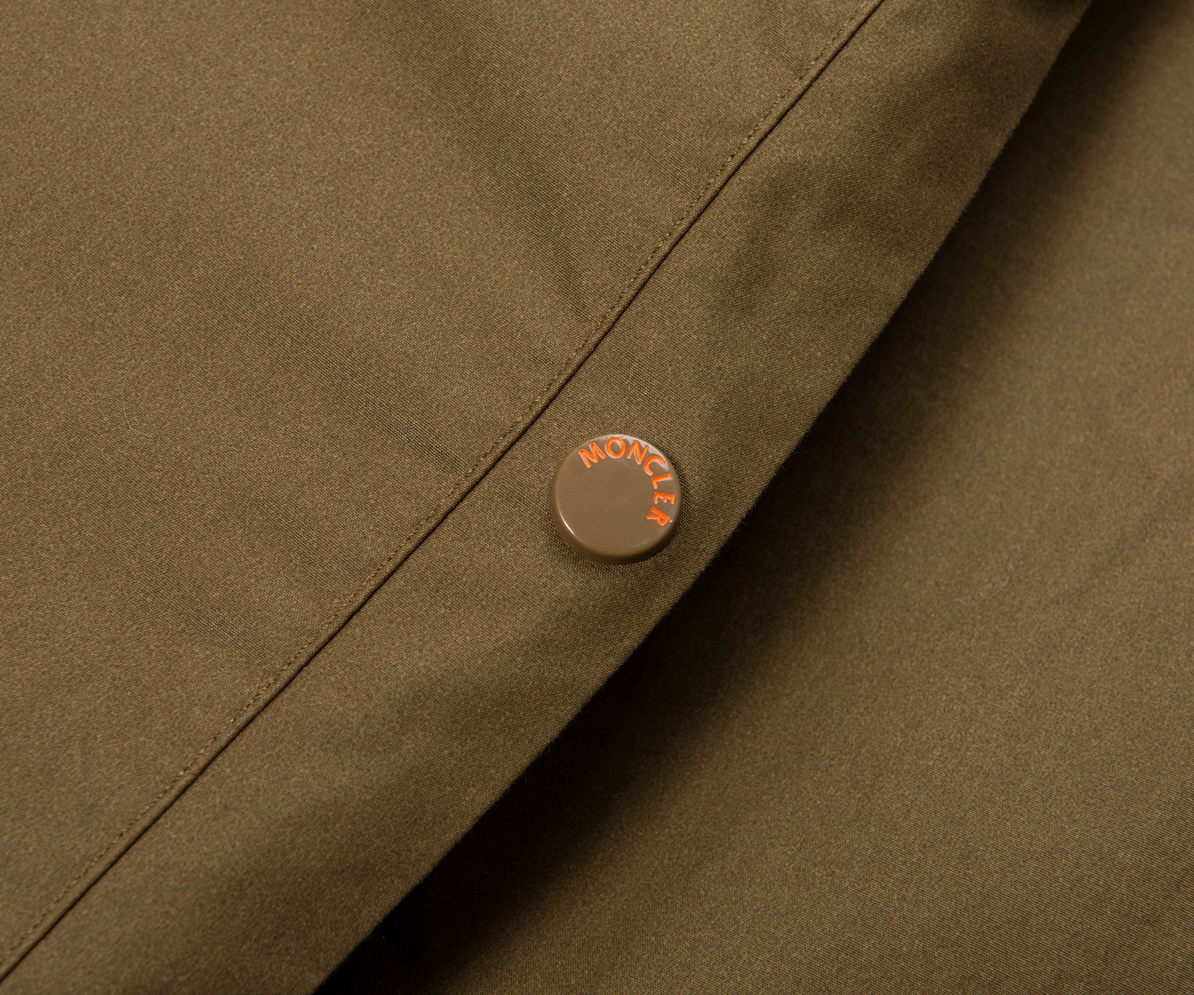 Close-up of a brown jacket with a brand logo on a matching background
