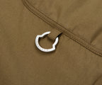 Close-up of a silver carabiner attached to a brown fabric surface.