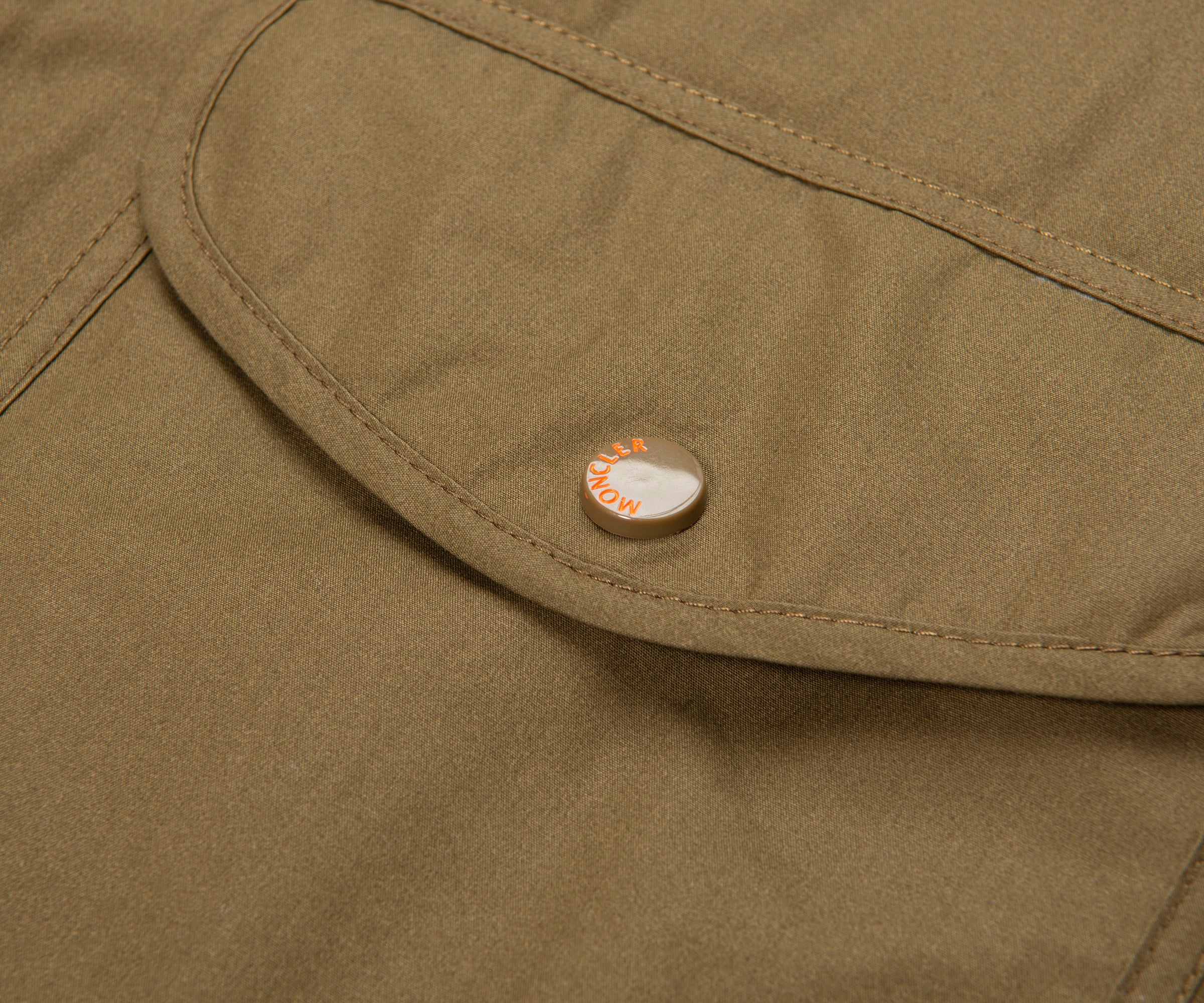 Close-up of a green jacket with a brand logo on a button.
