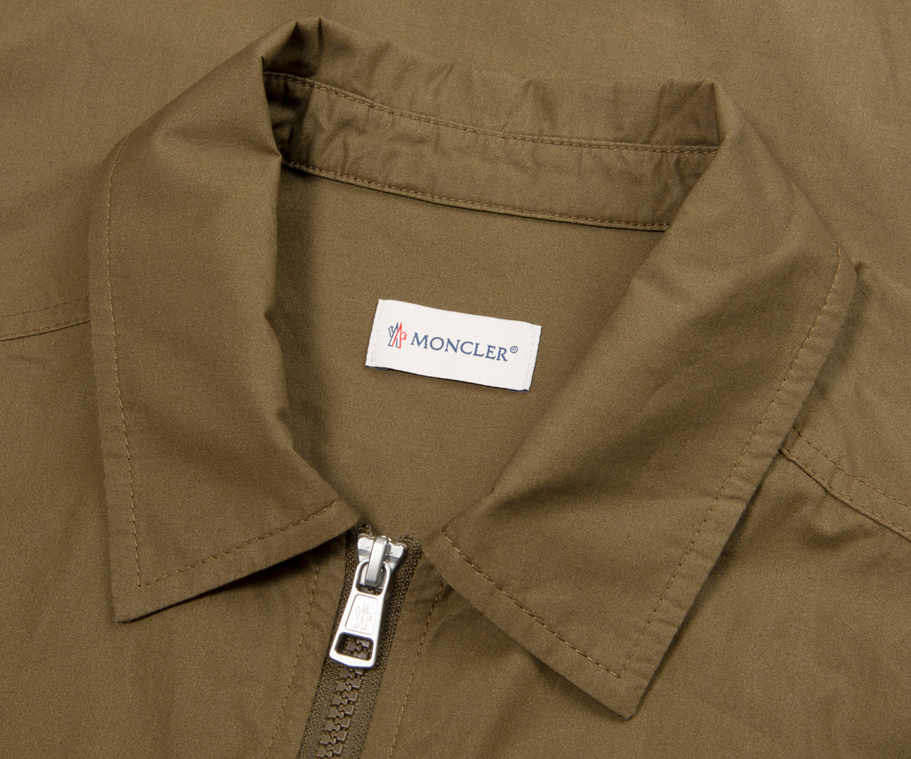 Close-up of a Moncler label on a brown jacket collar.