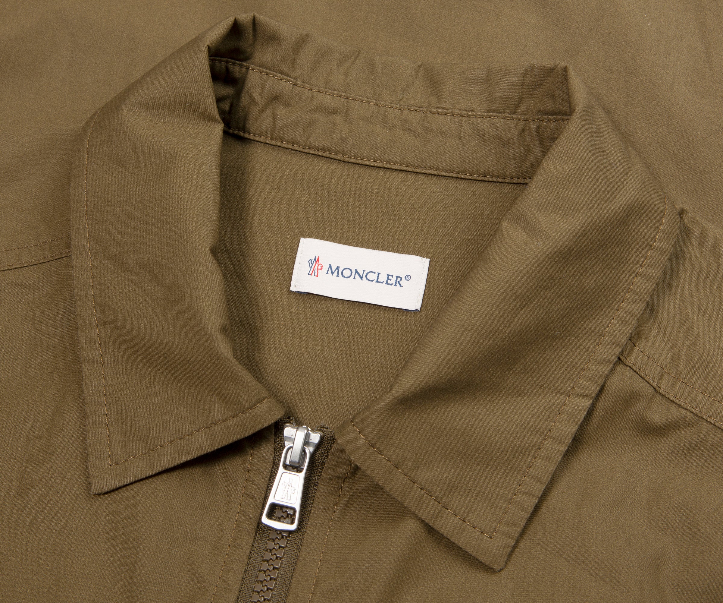 Close-up of a Moncler label on a brown jacket collar.